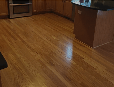 Kitchen with light brown hardwood floors, wooden cabinets, an oven, and a dark countertop island.